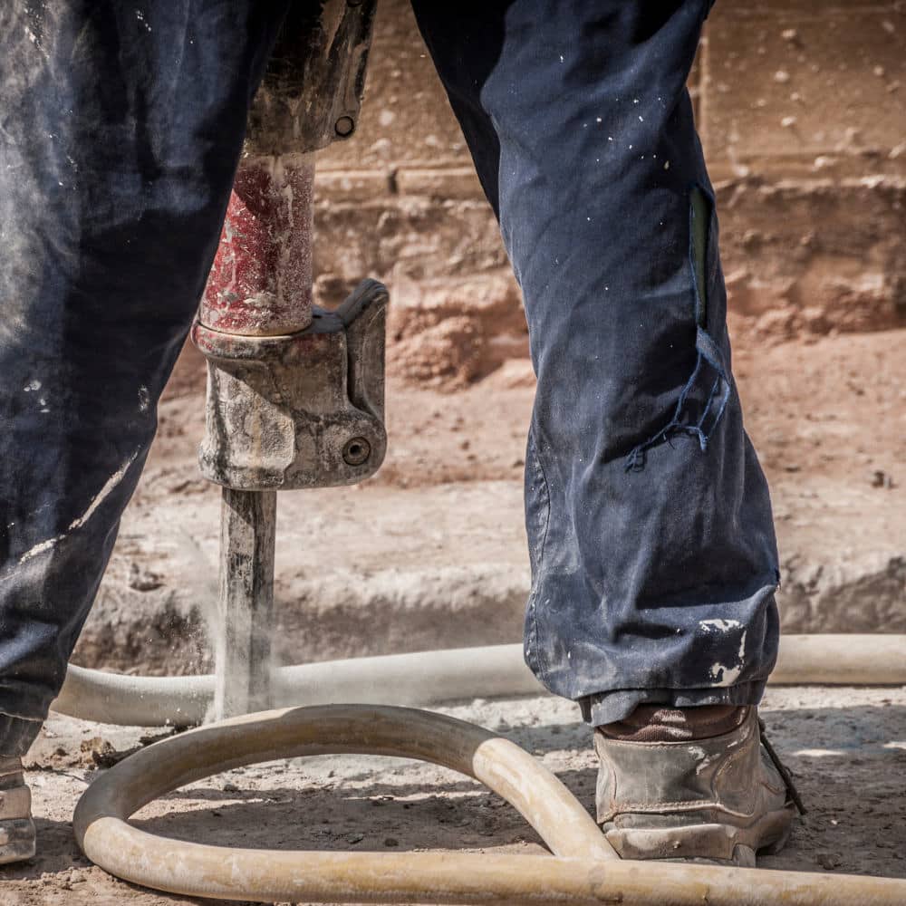 Man using a jackhammer to remove concrete